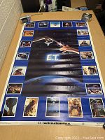 Full view of the vintage E.T. poster laid flat on table, showing main image and border stills from the movie.