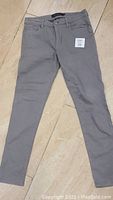 Full view of gray Calvin Klein women's jeans laid flat on floor.