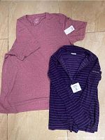 Photo showing both shirts side by side, pink short sleeve t-shirt and purple striped Columbia blouse on tile floor.