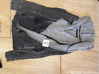 Top-down photo of the Blanc Noir jacket spread flat showing full front with zip, hood, and sleeves.