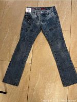 Full front view of blue denim jeans pants laid flat showing pants overall shape, legs, and pockets.