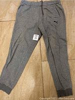 Gray Puma sports pants shown fully extended, highlighting the elastic waistband with drawstring and Puma logo on the left thigh.