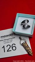 Sterling silver adjustable ring with engraved detailing and a leopard print pointed pendant with silver bail in a light blue jewelry box, displayed against a red background with auction information.