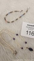 Necklace and bracelet laid on white fabric with MaxSold tag visible