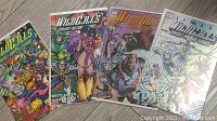 Set of four Wildc.A.T.s comics in protective plastic sleeves, colorful superhero covers visible.