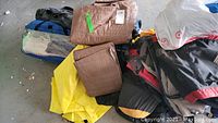 Overview photo showing blue family dome tent bag, multiple brown tarps, yellow tarp, and several duffel bags in black and red colors