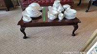 Photo showing finished wood coffee table top with white dishware stacked on it, showing size and condition of table.