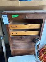 Front view of wooden file cabinet showing open drawers and tambour door panel.