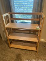 Front view of wooden folding shelf unit showing three shelves and side slats.