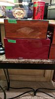 Photo of two stacked wooden humidors with size labels on the front, polished exterior woods (brown and red finishes).
