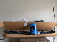 Golf clubs arranged inside a long open cardboard box.