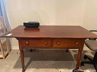 Front view of wooden desk showing two drawers with wooden knobs and medium brown finish.