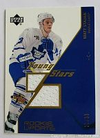 Front view of the 2004 Matt Stajan Young Stars Rookie Update hockey card showing two embedded pieces of white jersey fabric and card numbering 07/99.