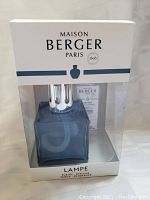 Front view photo of sealed Maison Berger Paris Lampe Berger lamp box showing the blue glass lamp inside plastic packaging.