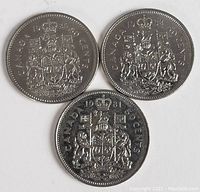 Obverse side showing detailed Canadian coat of arms and denomination 'CANADA 50 CENTS' on three coins; one dated 1931, two dated 1982.