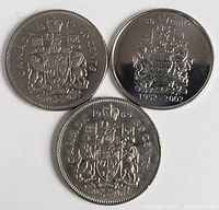 Three Canadian fifty cent coins showing the side with the Canadian coat of arms and years 1969, 1976, and 1922-2002 commemorative coin.