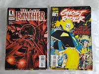 Photo showing Black Panther #10 comic with predominantly red and black cover art and Ghost Rider comic featuring fiery skeleton on motorcycle.