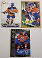 Front view of three Connor McDavid hockey cards showing player images and designs.