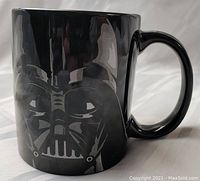 Front side view of black ceramic coffee mug featuring etched Darth Vader helmet design with glossy finish and no visible chip or cracks.