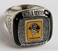 Front view showing the Pittsburgh Pirates logo in yellow rectangle with surrounding stones and black enamel, and inscriptions 'WORLD SERIES' and 'CHAMPIONS'.