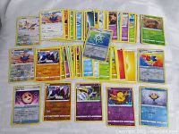 Image showing assorted Pokemon cards laid out on white surface including some foil cards and various energy types.