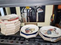 Stack of vintage boxed plates with some plates removed from boxes for display.