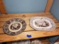 Photo showing two large antique porcelain plates side by side on a wooden surface, highlighting their size, shape, and detailed border patterns.