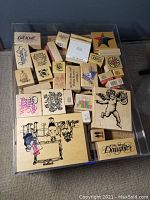 Photo of assorted wooden craft rubber stamps in a clear plastic tray including text and image stamps