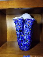 Front view of blue Josefina glass vase with colorful speckled spots and ruffled top edges.