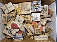 Box filled with assorted craft rubber stamps on wooden blocks, showing various artistic and text designs.