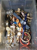 Large assortment of mixed women's watches and bracelets in plastic bin, showing various band materials including metal, leather, denim, and plastic.