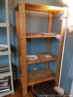 Full view of wooden slat shelves with four levels and decorative plates.