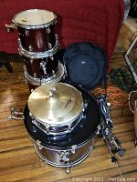 Photo showing bass drum, snare drum on top, rack toms stacked, hi-hat pedal visible.