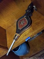 Full view of vintage fire bellows showing wooden frame, leather panels decorated with metal studs forming star and diamond patterns, and metal nozzle