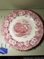 Full view of the Wedgwood pink turkey design porcelain plate with floral border, mounted for display.