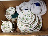 Top view of stacked teacups and plates showing floral strawberry vine pattern and gold trim