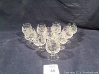 Full set of 10 crystal snifter glasses arranged on dark cloth background showing overall quantities and condition.