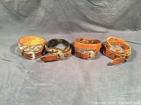 Four western style belts shown side by side on a gray background.