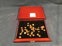 Opened wooden coin display case showing scattered Canadian pennies inside coin slots.
