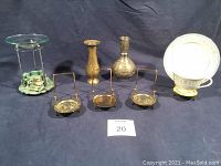 Photo showing four Barritt polished brass-tone teacup display racks, two vases (one silver plated brass and one brass), and a potpourri warmer, all arranged on dark background.