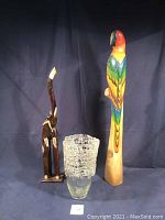Wood hand carved painted elephant sculpture, wood hand carved painted parrot on perch sculpture, and handmade glass vase displayed together