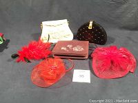 Overview of 6 evening accessory items including 3 bags and 3 fascinators arranged on black surface