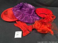 Full set of six items displayed on black fabric: purple chiffon hat, two red hats, two red fascinators, red lace gloves