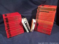 Photo showing stacked red hardcover Popular Mechanics Do-It-Yourself Annual Yearbooks from 1971 to 1989 with four novels in the center.