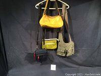 Four bags hanging from hangers against black backdrop, showing overall lot contents