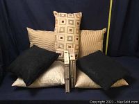 Seven assorted throw pillows arranged on a surface with a measuring tape for size reference.