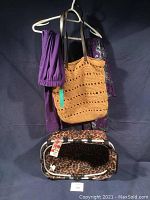 Photo shows hanging tan crocheted shopping bag, two leotards (purple and patterned), and faux leopard print shopping tote on the floor.