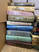 Stack of hardback books showing titles including The Limerick, The Long Way Home, Tom Wolfe, Three Storied Mountains by John Parris, Cold Service by Robert B Parker, Peachtree Road by Selden