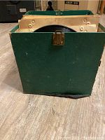 Front view of green cardboard box holding vintage records.