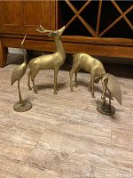 Three bronze animal statues shown together on floor, two cranes and two deer, highlighting size and finish